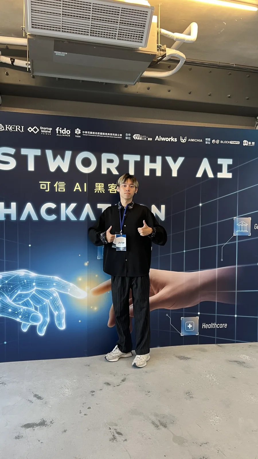Zuemen Chu wearing a staff lanyard in front of the Trustworthy AI Hackathon 2026 backdrop